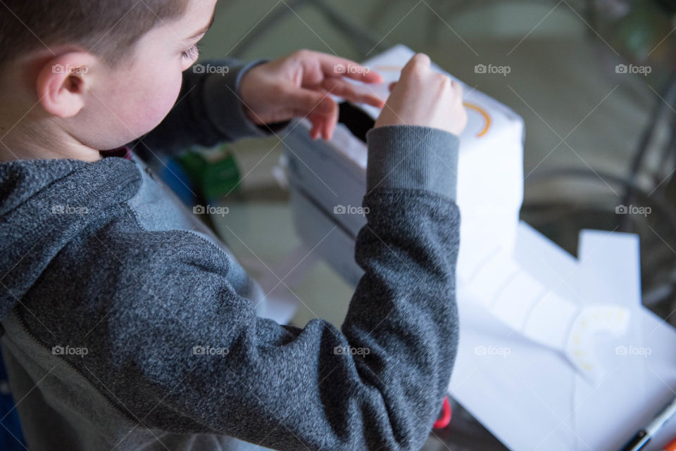 Young school aged boy making a cardboard robot at home