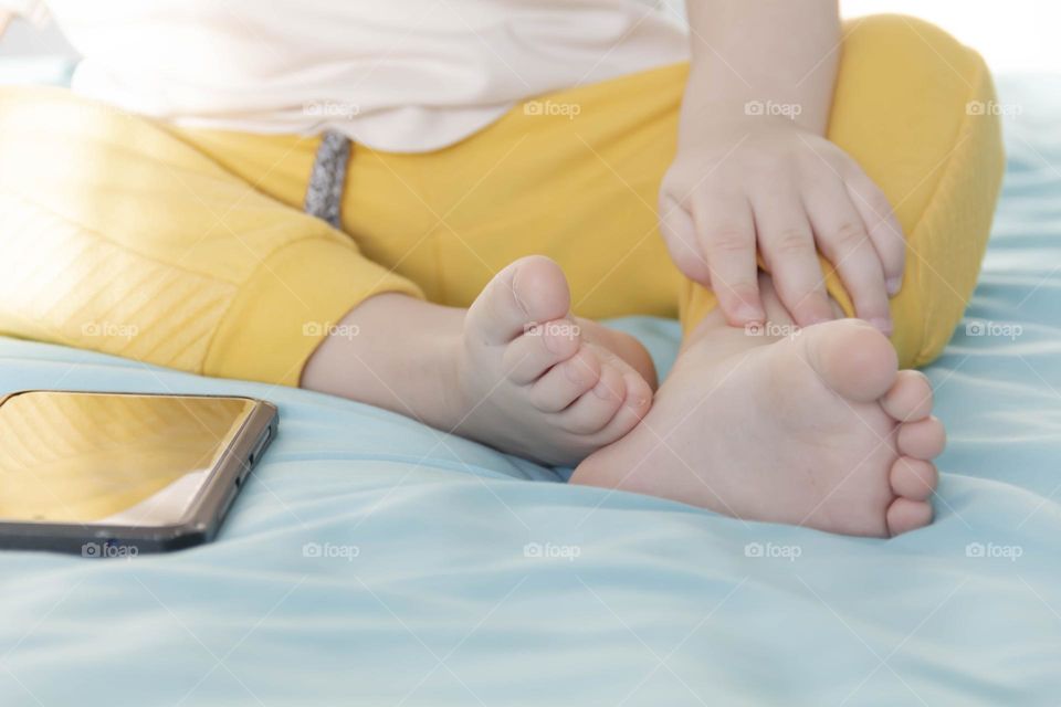 Little children's feet barefoot in yellow pants.