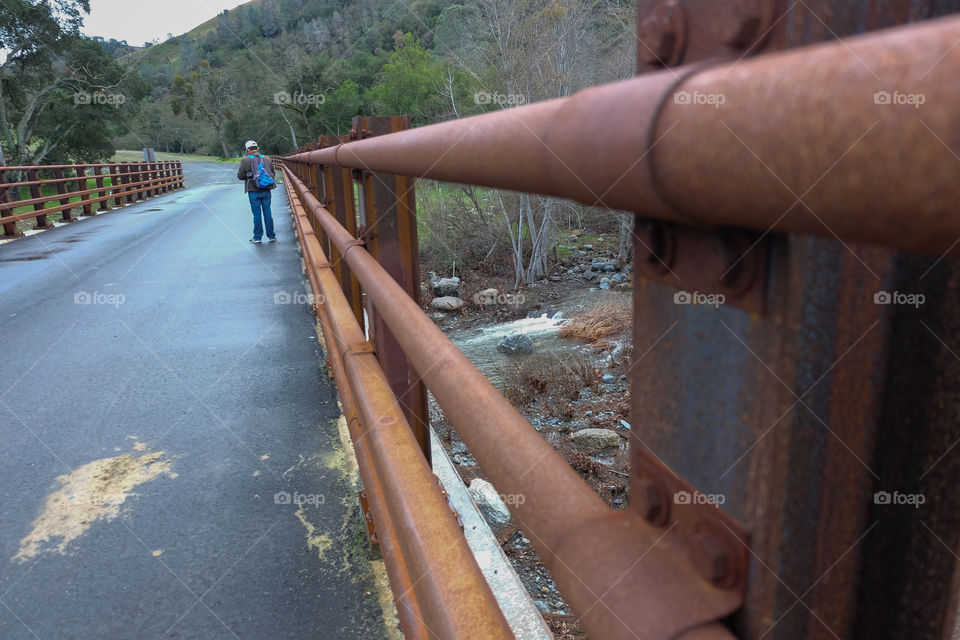 Hiker on rusted b
ridge , river flowing underneath