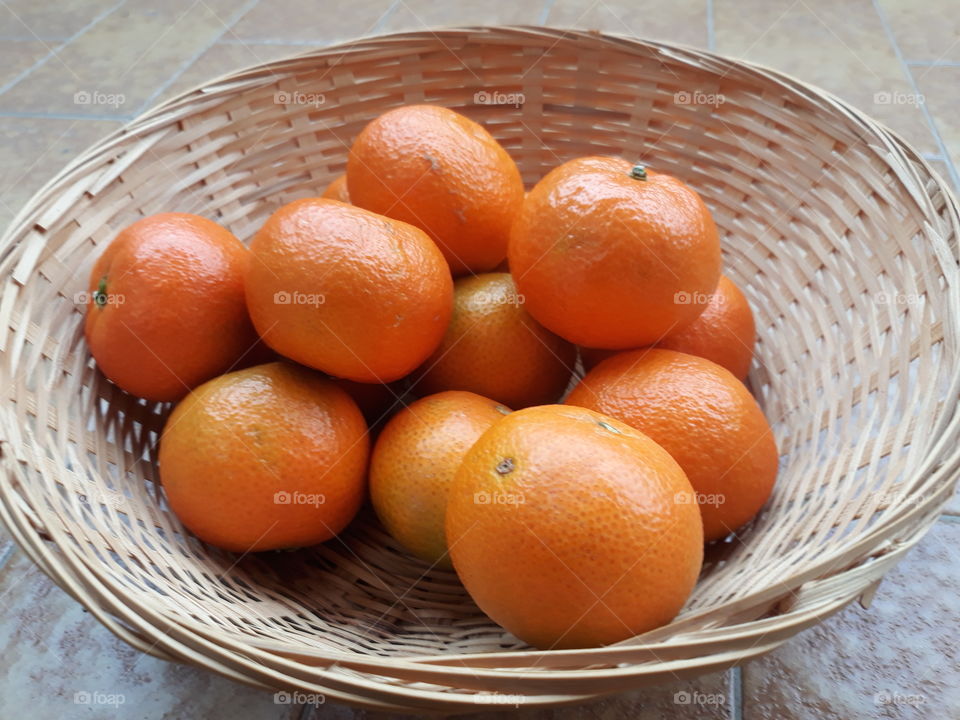 A cest of brilliant orange tangerines, with the Gray light of a cloudy morning in italy