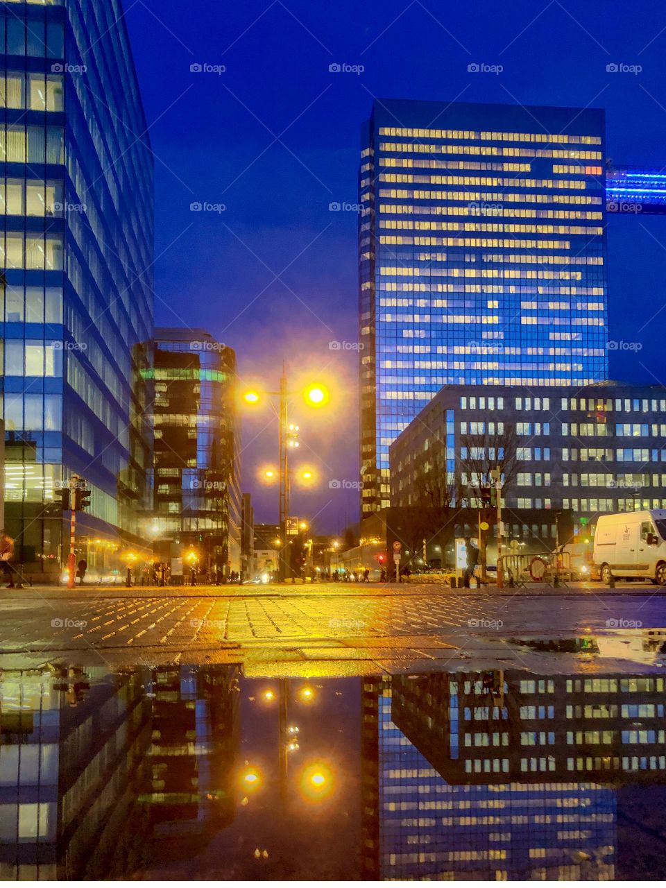 Business offices in the city at Dusk reflected in the water of a puddle on the streets