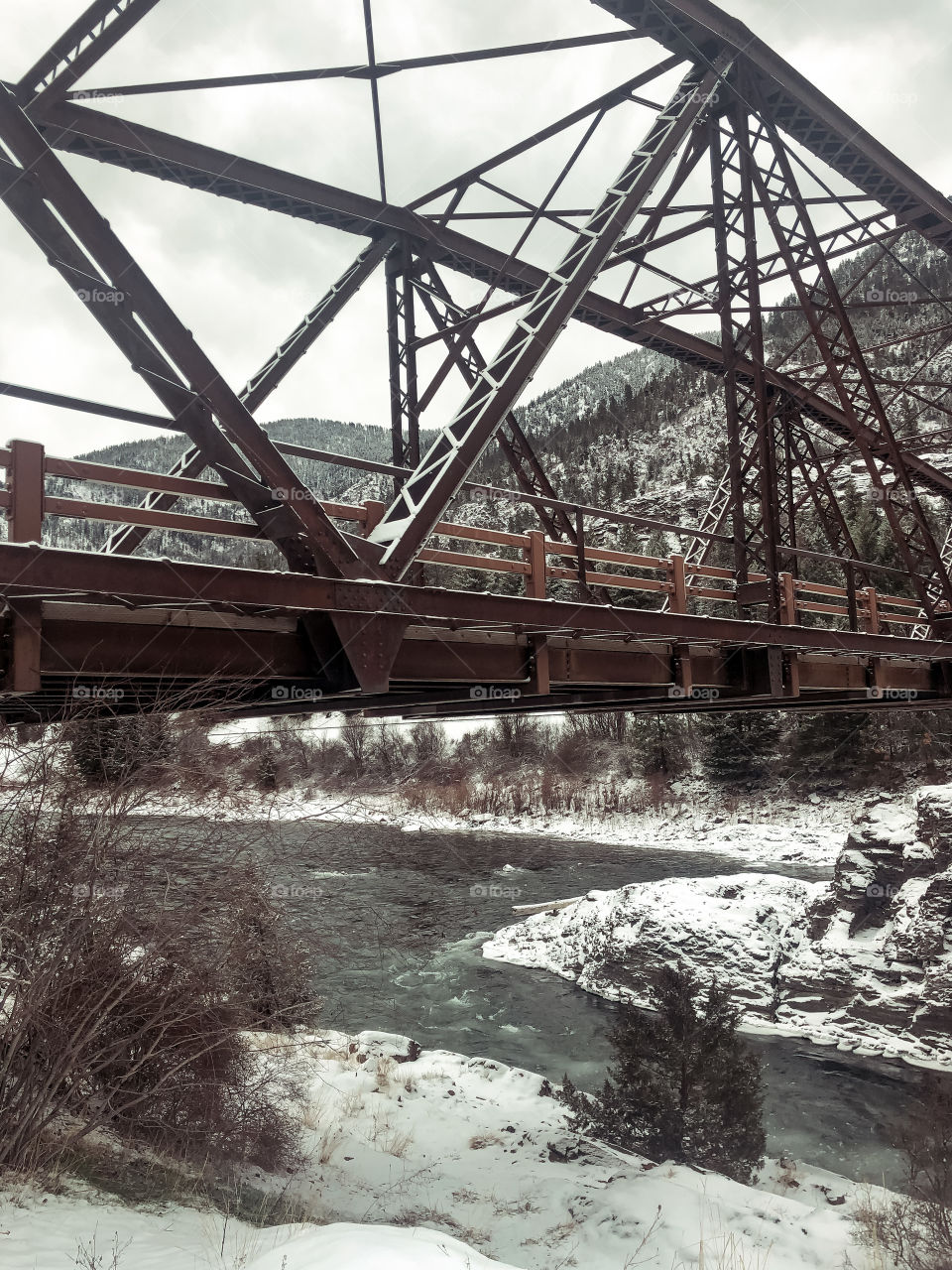 Beautiful icy and snowy bridge over a frozen river in winter in Montana. 