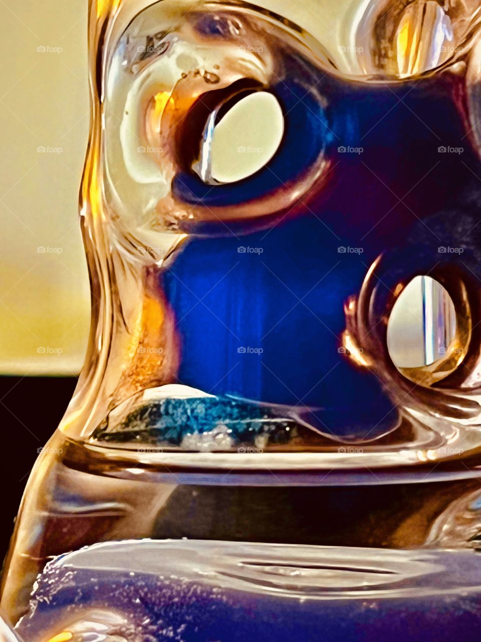 Glass sculpture holding water and reflecting colors.