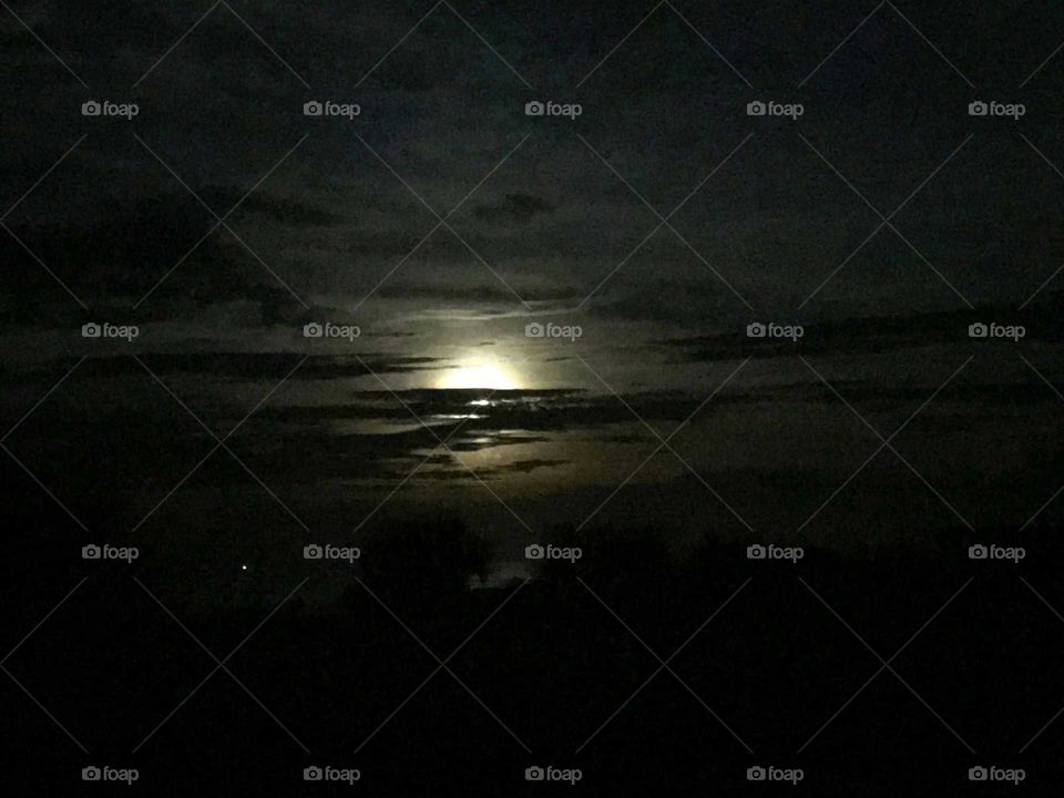 Super moon over the Atlantic Ocean in New Smyrna Beach, Florida. This thing was so bright, shot from my girlfriend's iPhone 7. This camera phone did a little better than my ZTE, but still doesn't capture the full moon as my eyes saw it. Still looks good with the light clouds passing through.
