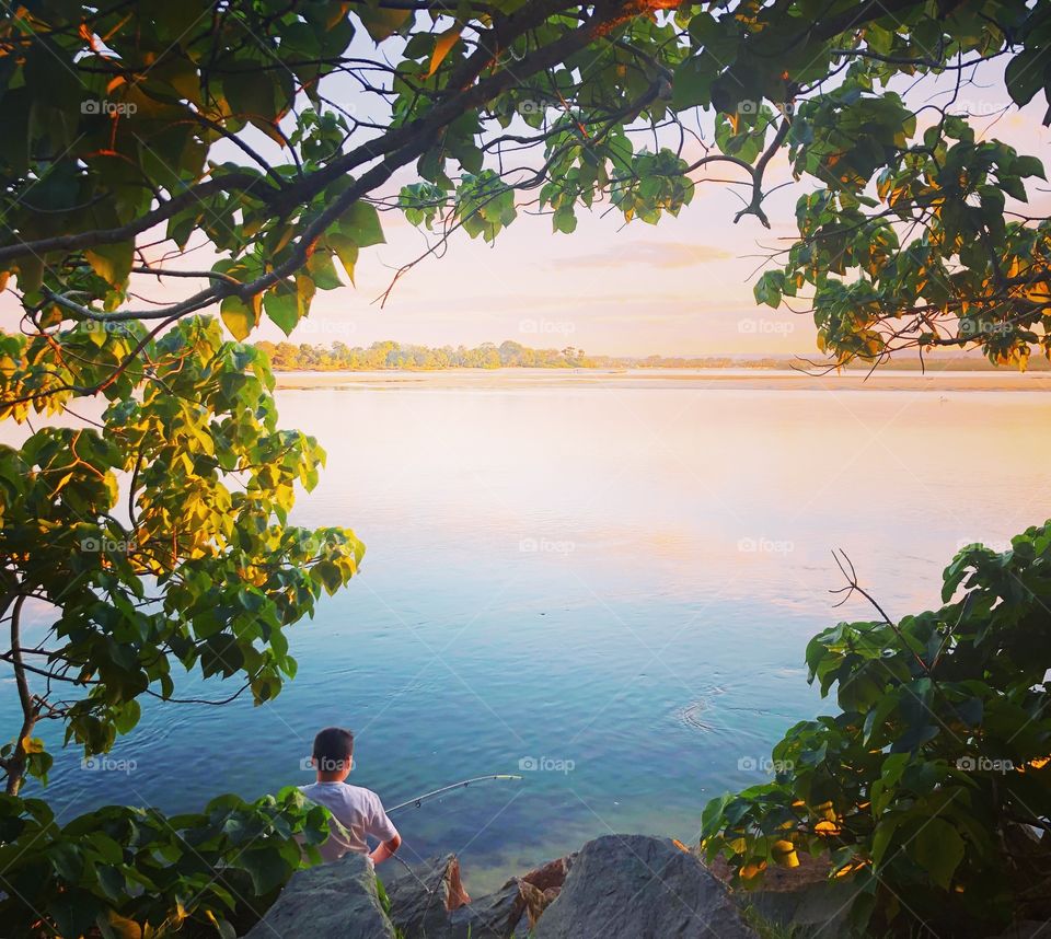 Fishing at the river trees on the path framed by leaves
