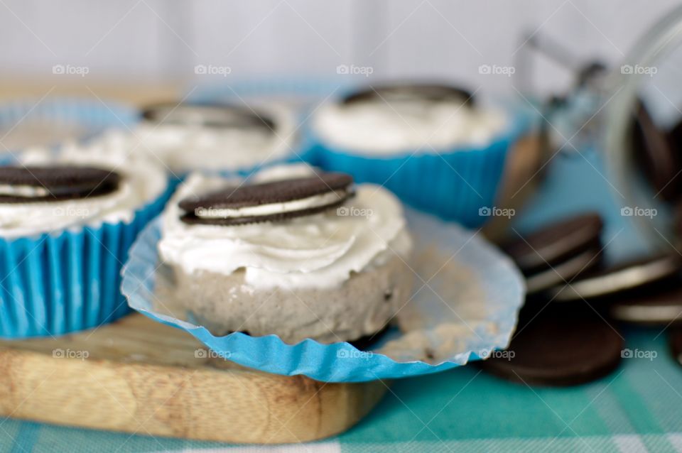 Oreo cookie ice cream cupcakes on a wooden board and white and blue background 