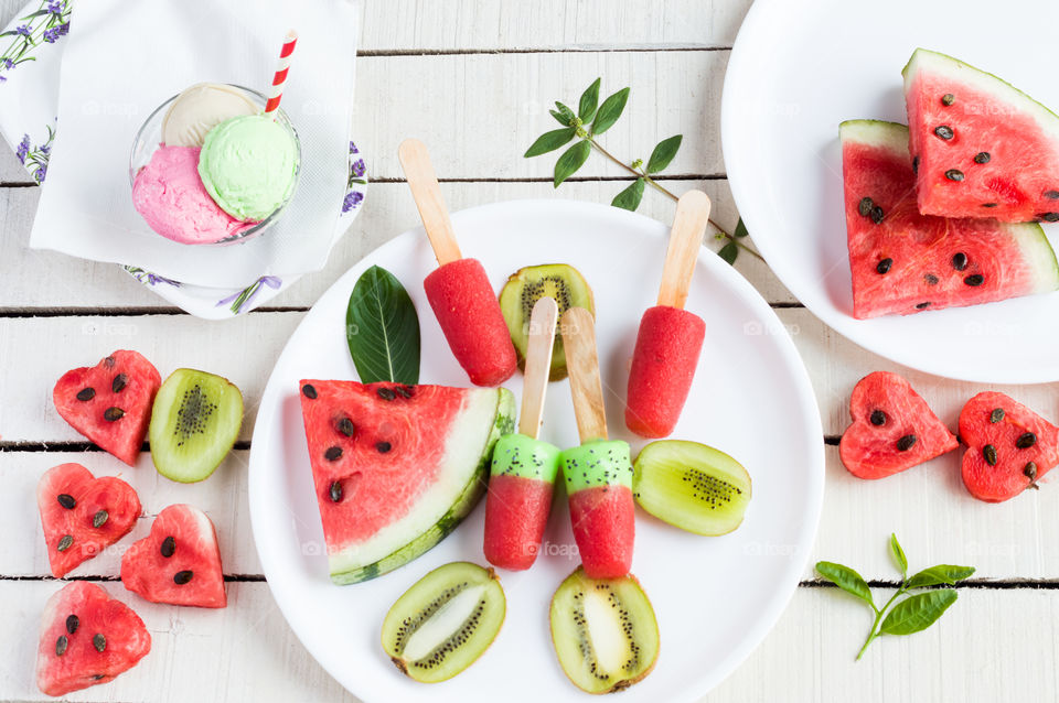 Flatlay of watermelon kiwi popsicles isolated on white background.