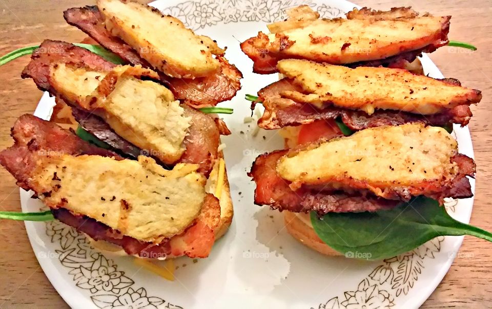 a marinated grilled chicken bacon sandwich with tomatoes onions and baby spinach.
