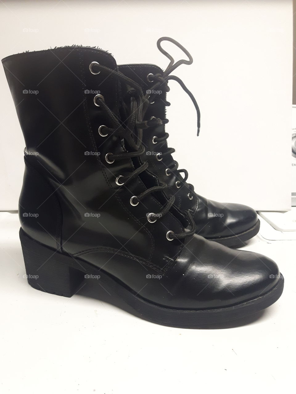 A pair of straight laced black patent leather boots that shine