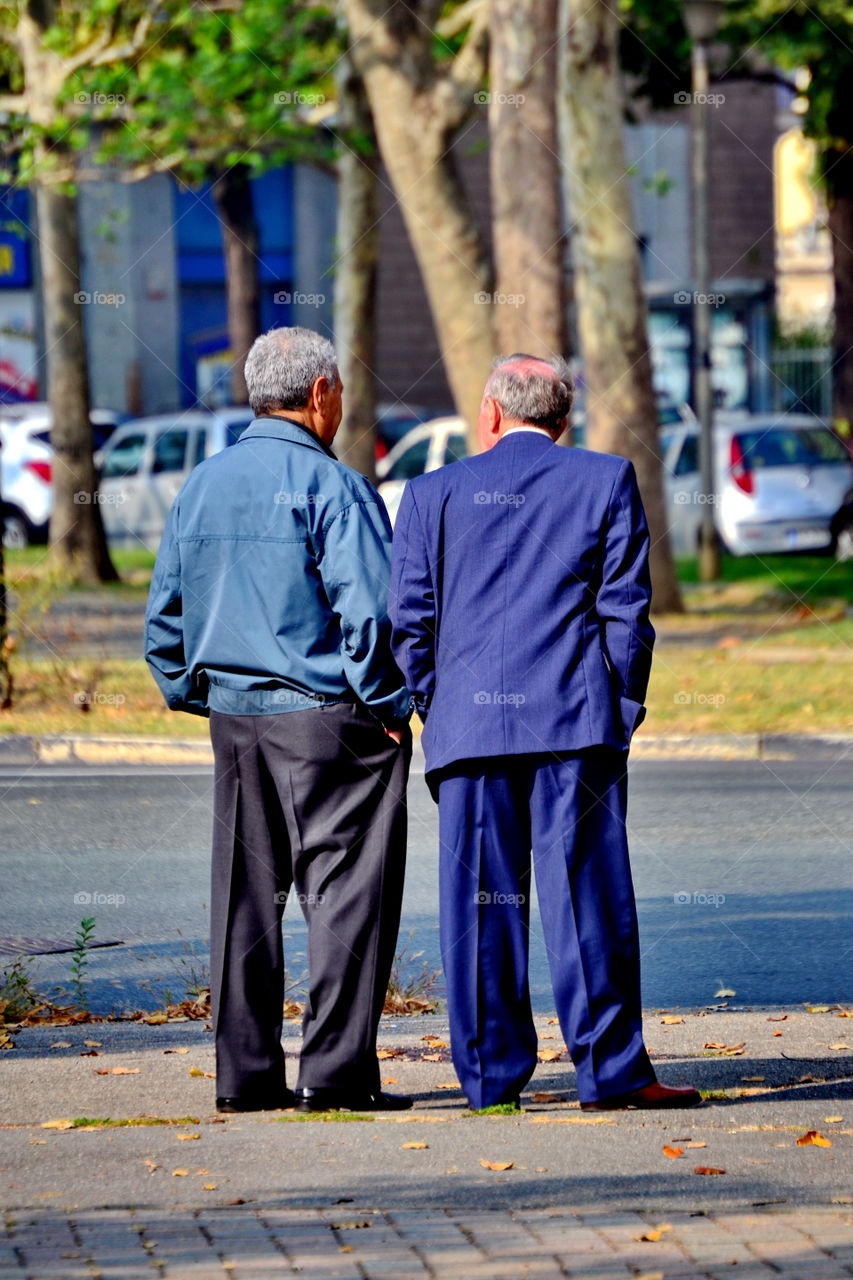 two older men standing chatting in the street