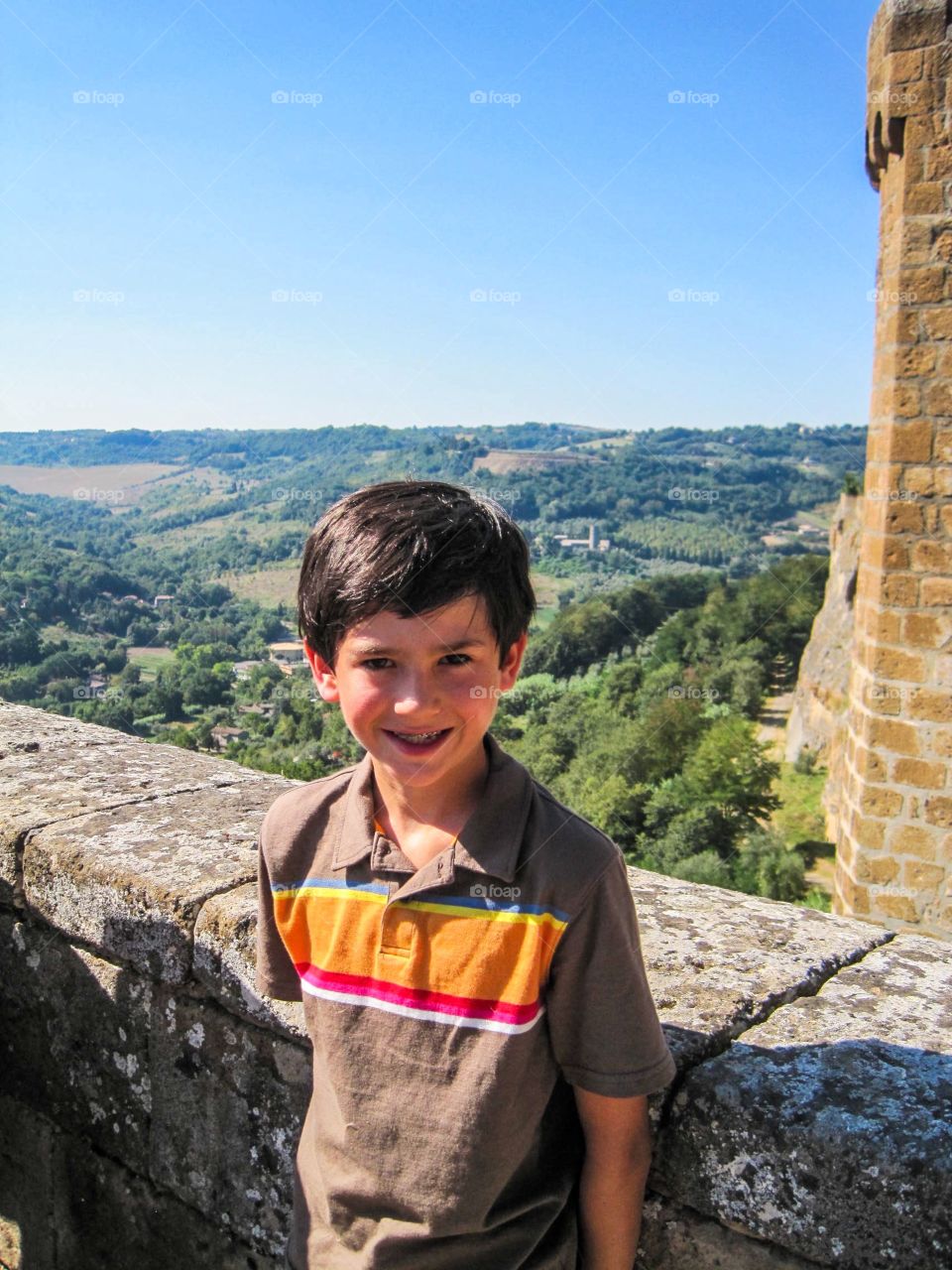 A boy nicely dressed with a lush Italian landscape in the backgroun 