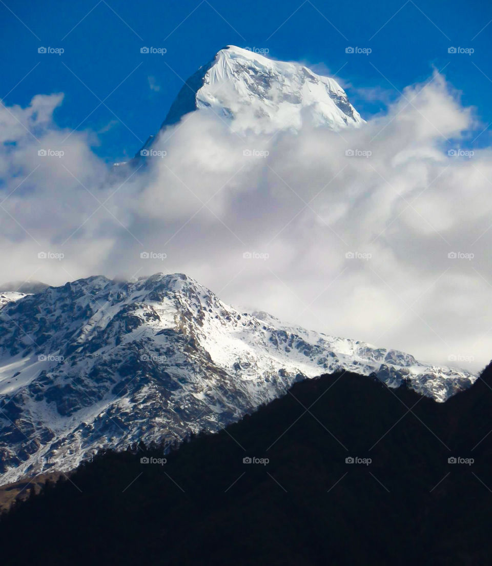 The clouds have a tendency to start coming in as the day heats up. This is a photo of Annapurna South. Photo taken on the Annapurna Base Camp Trek in Nepal.
