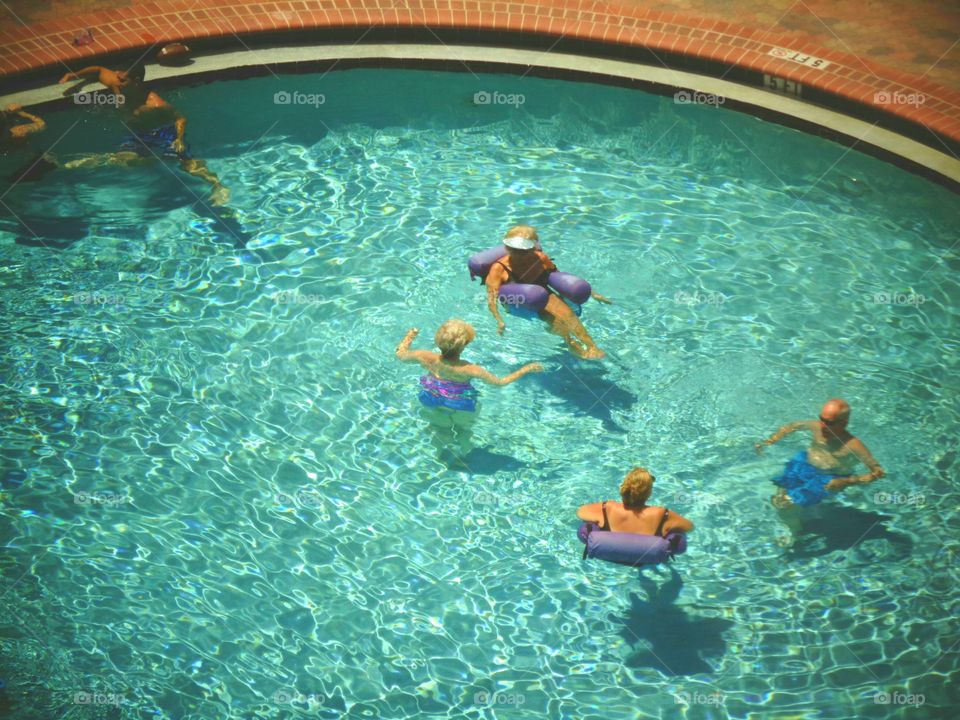 Round swimming pool, people having fun, floats, laughing, vacation.