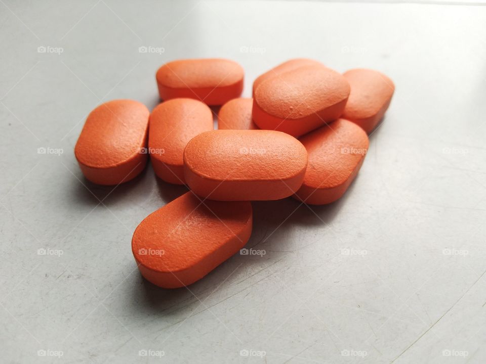 orange color medicine tablet is on doctor table