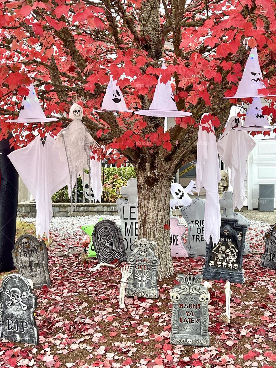 Halloween decorations on the tree. Ghosts, which hats, tombs, grave stones 