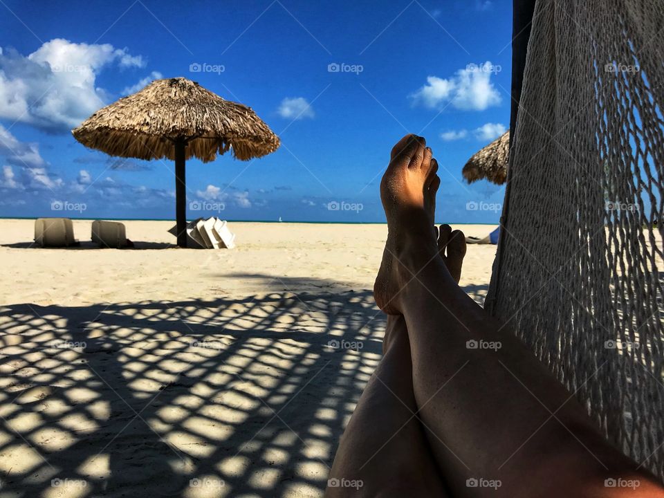 Person relaxing in hammock on beach 