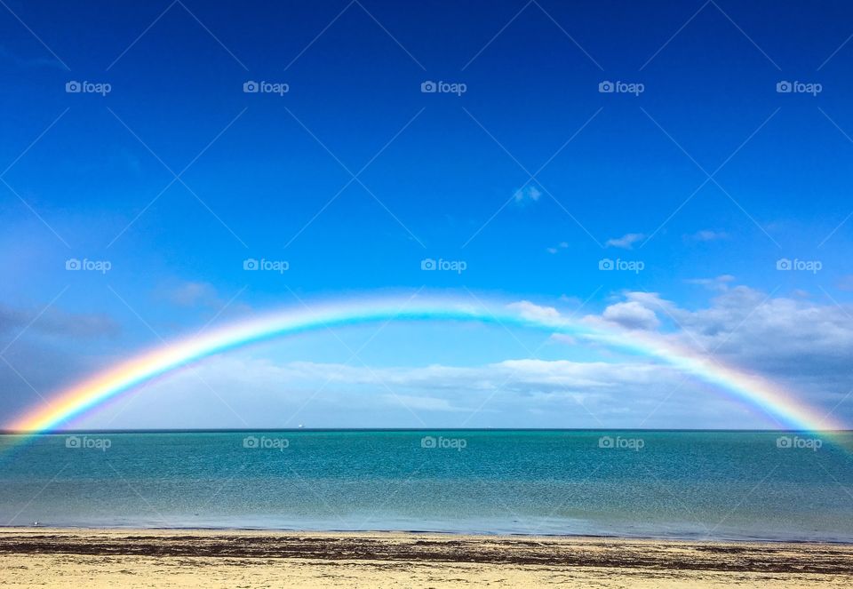 Rainbow over ocean on remote beach 