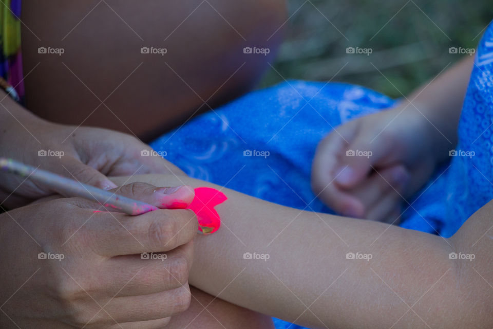 painting pink heart on kid arm