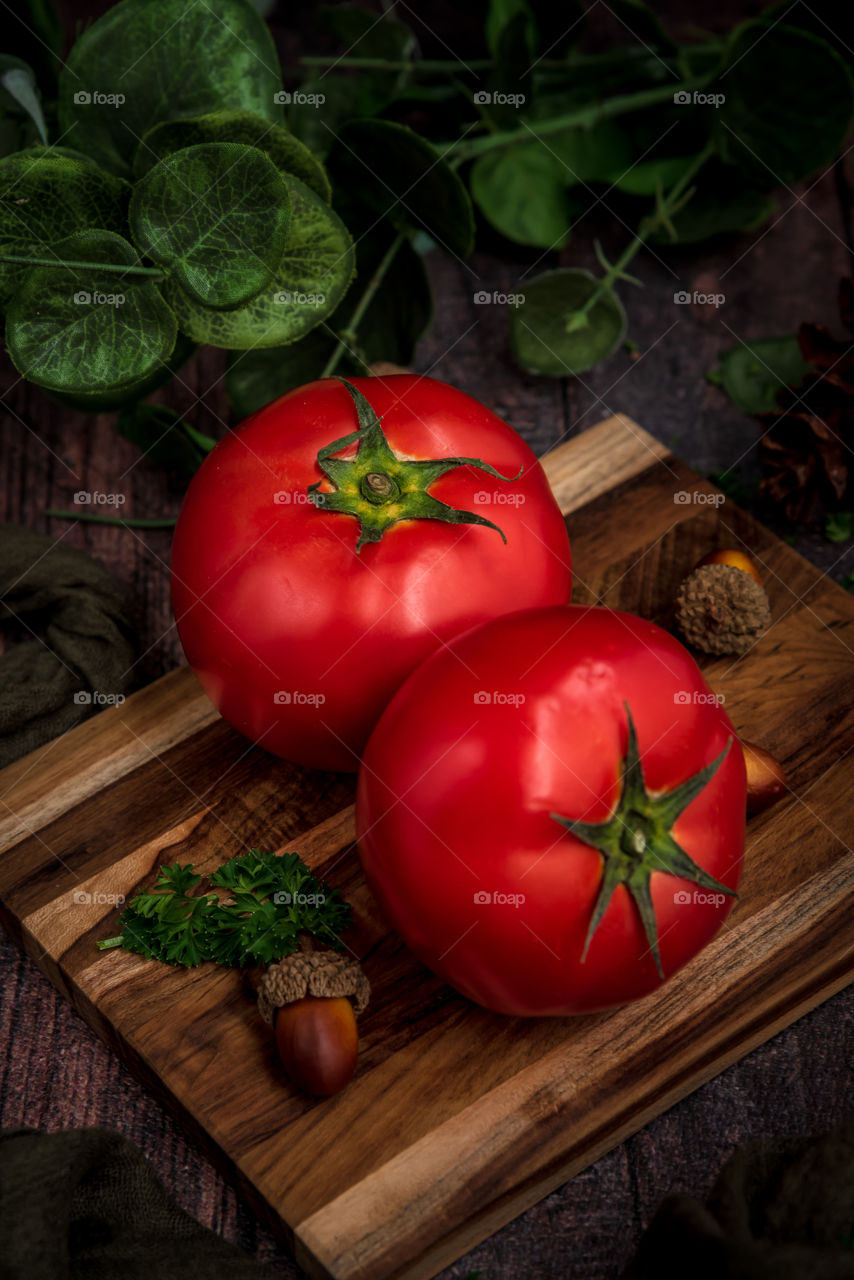 Two fresh red tomatoes on top of wooden tray