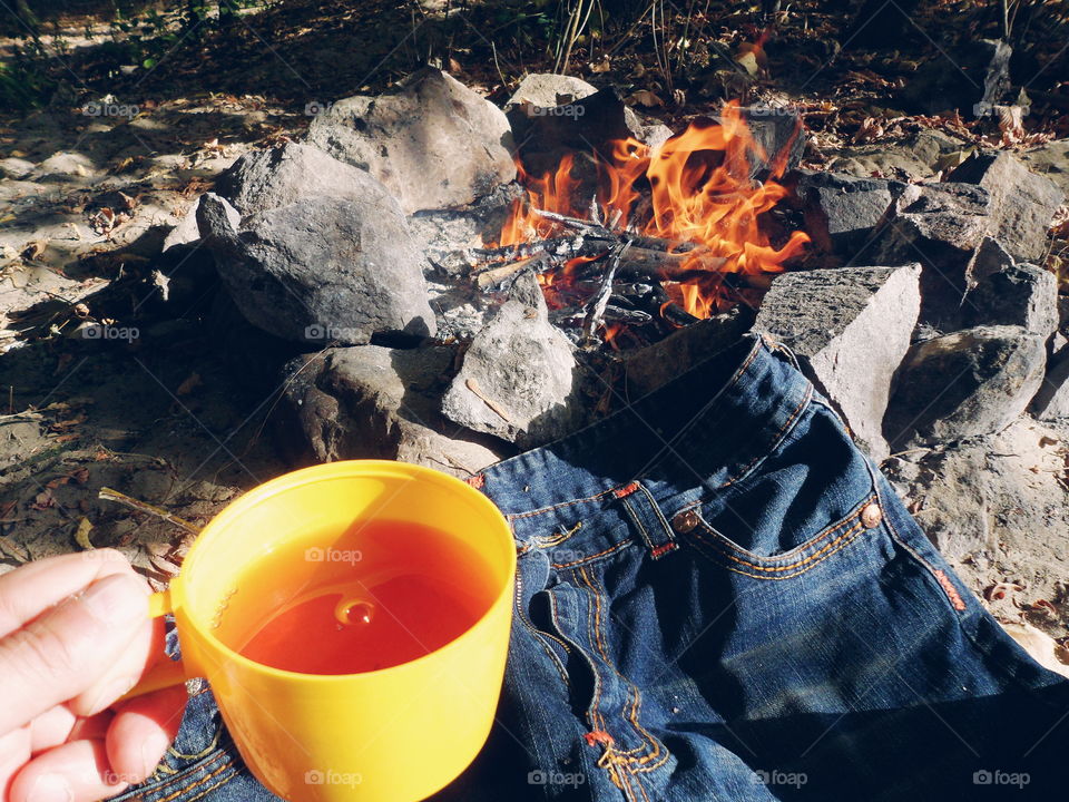 cup of tea and jeans near a fire