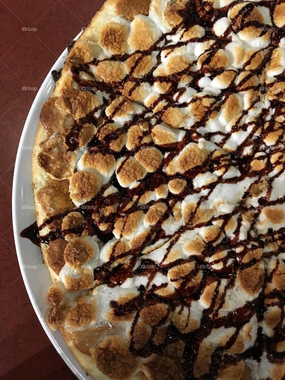 Pizza covered with peanut butter and topped with chocolate drizzle, graham cracker crumbles and marshmallows 