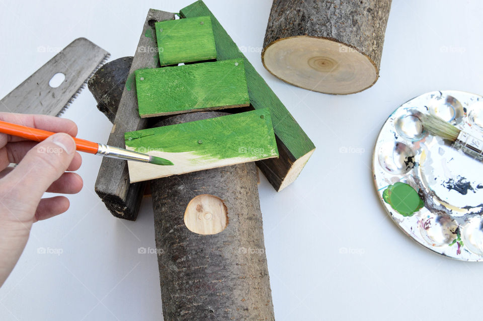 Person constructing and painting a birdhouse surrounded by craft supplies