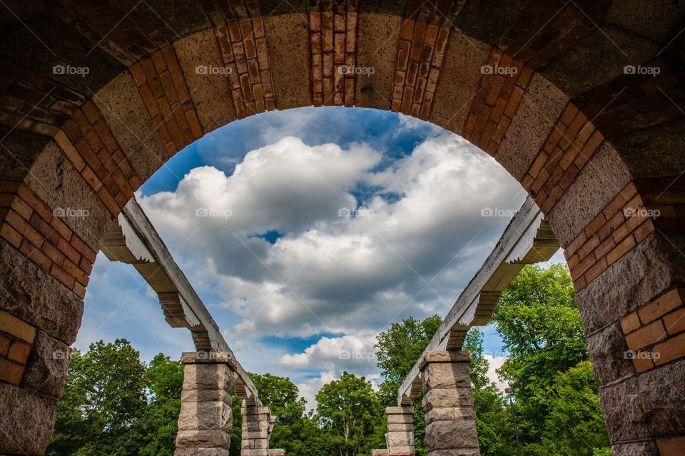Out an archway with some pillars and a bright blue sky