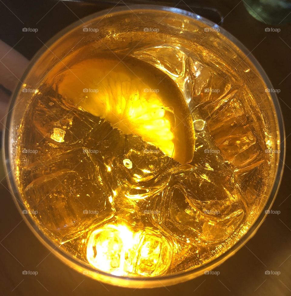 A clear and orange cocktail with ice cubes