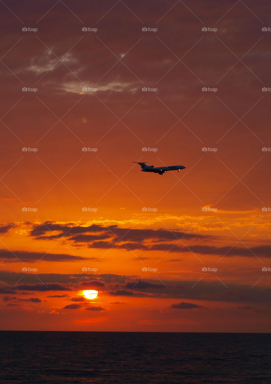 the silhouette of flying plane above the sea