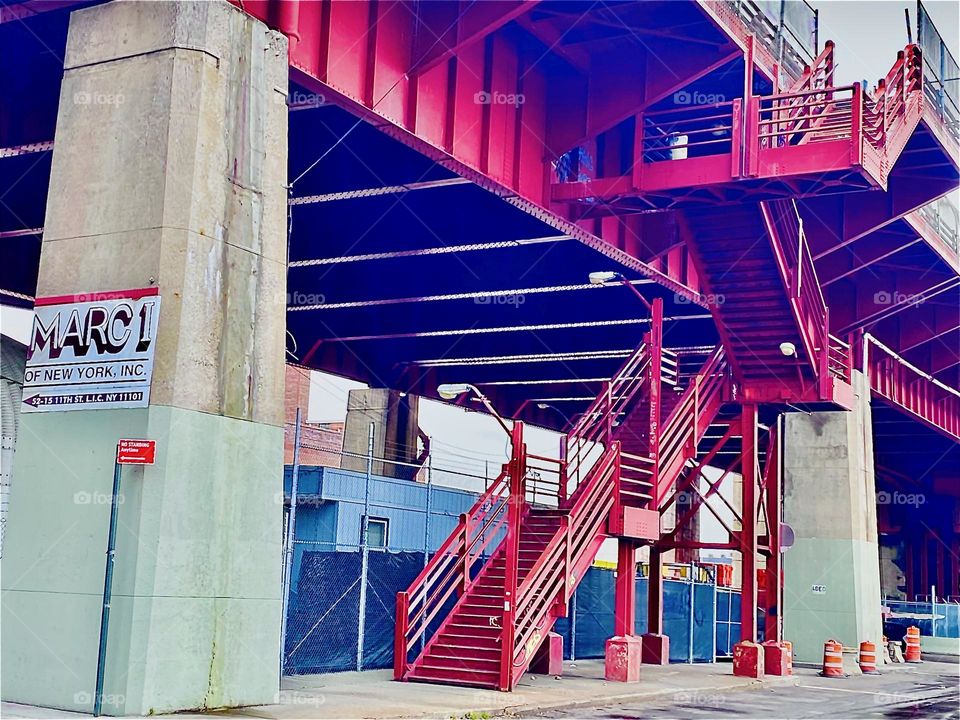 The res metal staircase leads up onto the Pulaski Bridge in LIC, Queens, NY spanning the East River at Newtown Creek to take cars, bicyclists and pedestrians across to Greenpoint, Bklyn. 2021. Hypnotic Productions