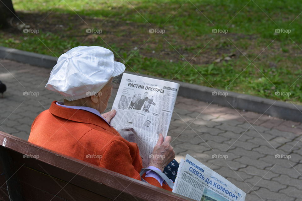 old woman resting and reading in the park