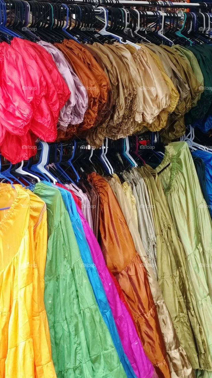 Rainbow of bright and colorful skirts and blouses at a market stall at a Renaissance festival