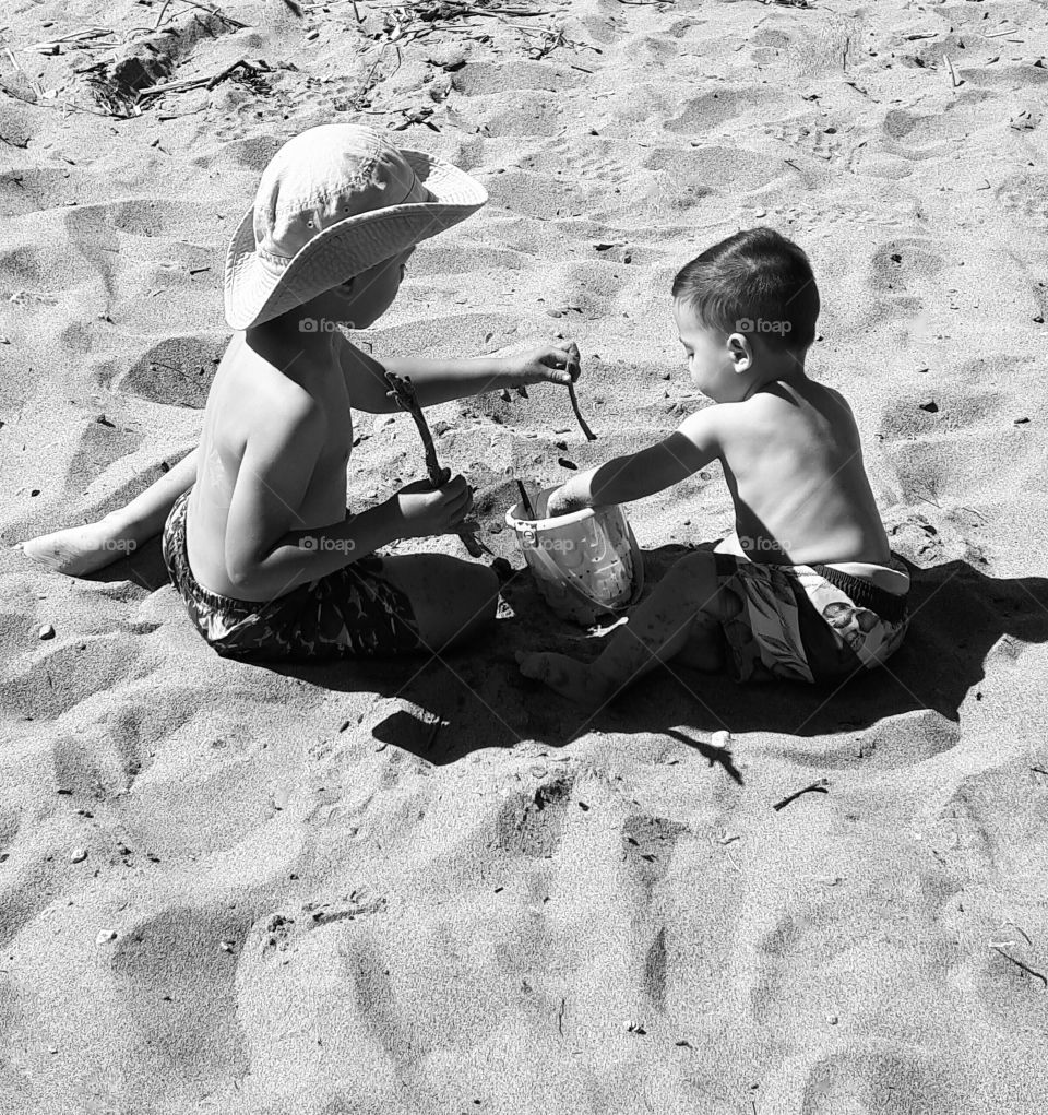 Two young boys playing in the sand on a beach