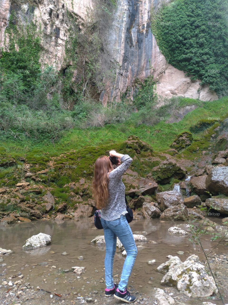 Una mujer de espaldas fotografiando la naturaleza