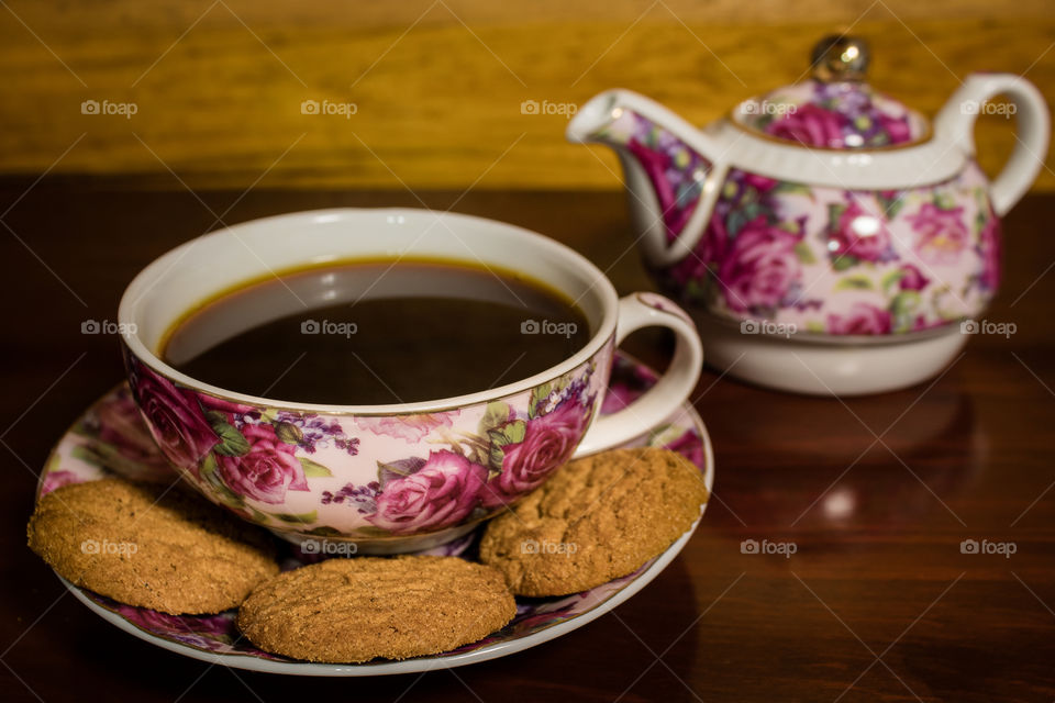 A coffee cup with a saucer and some oatmeal cookies
