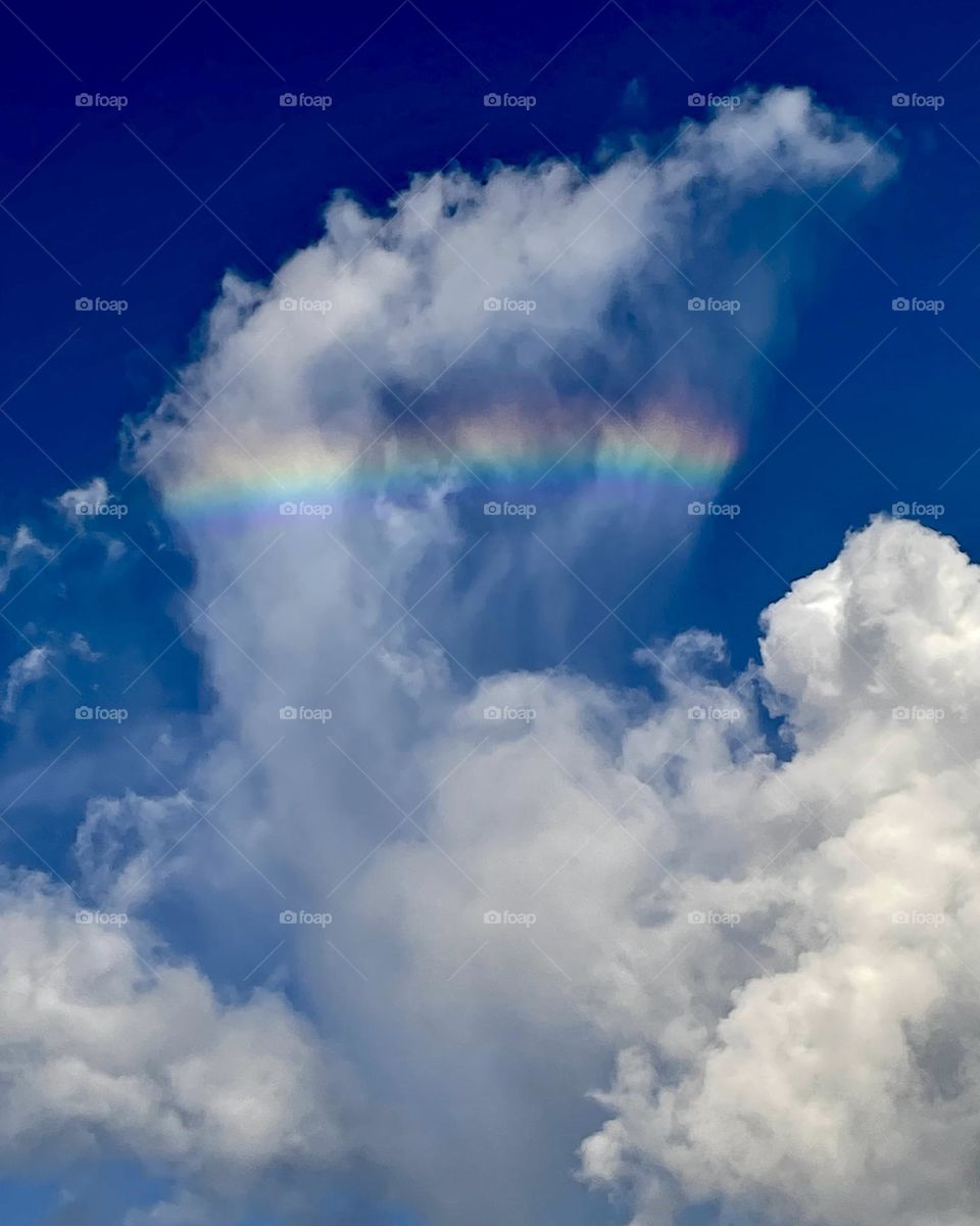 A very interesting looking cloud formation with a rainbow going through it