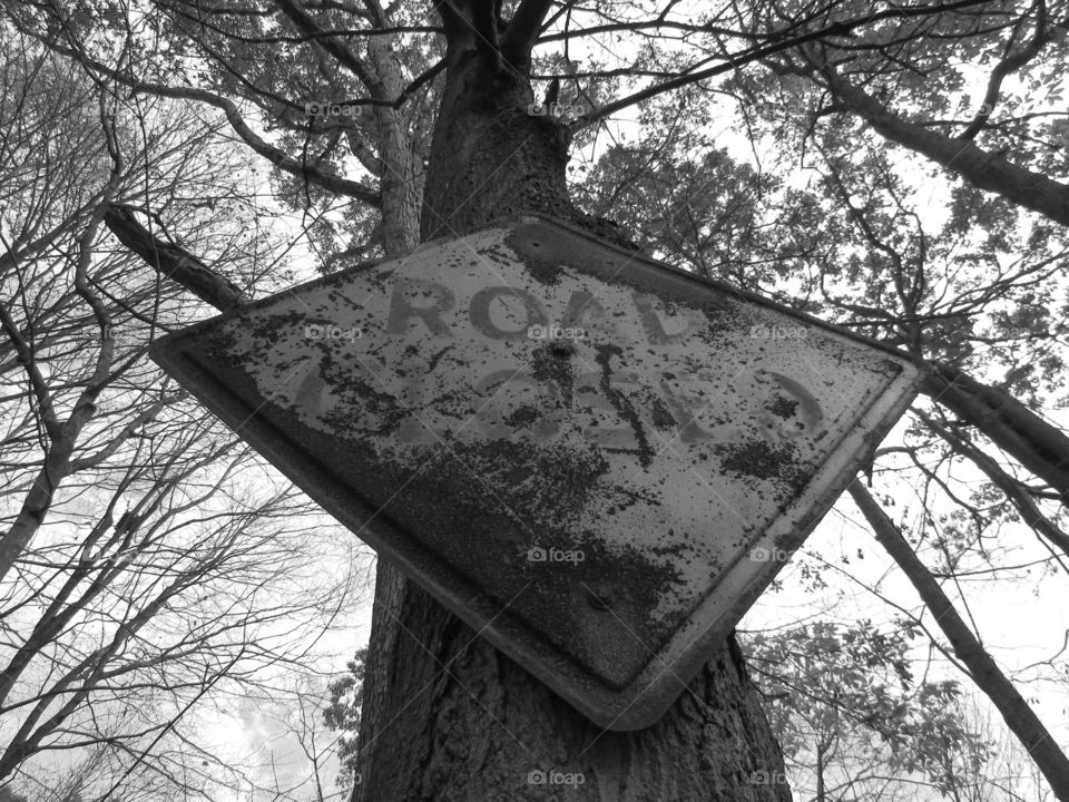 Black and white picture of a rusted road closed sign looking from the bottom up