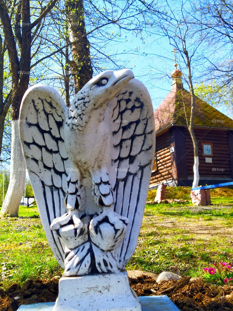 Sculpture of a clay eagle against the background of a rural church