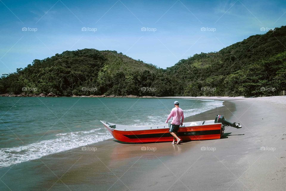 Sailor at Ubatuba, Brasil. Beautiful Shot of a boat and a man at the beach. Sunny Day.