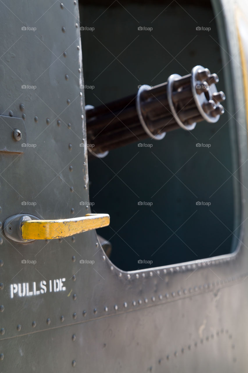 Machine gun sticking out from old Vietnam war helicopter door.