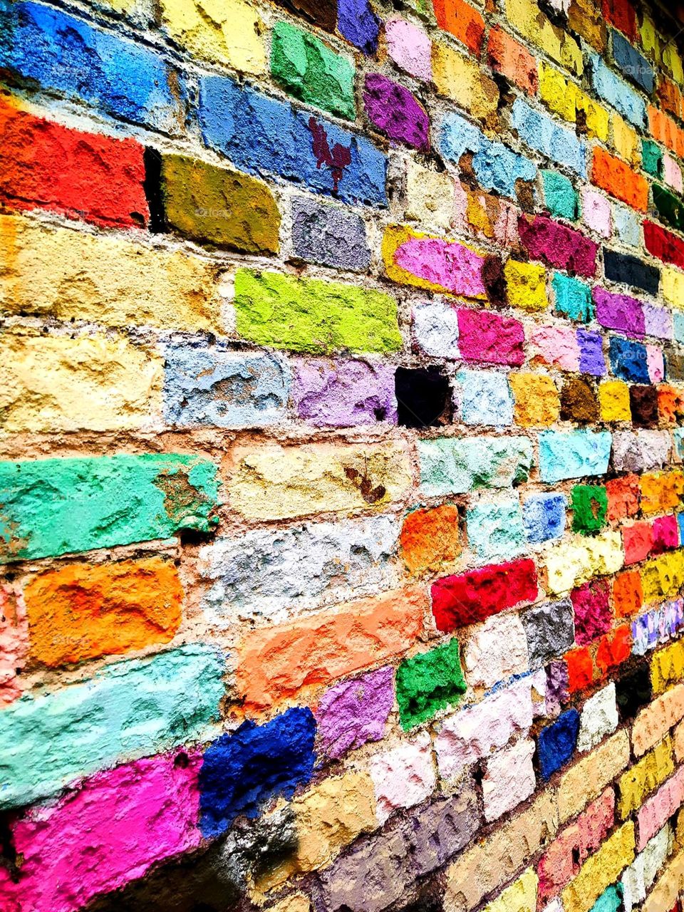 Brick wall painted in all colors.  Bright colored wall.