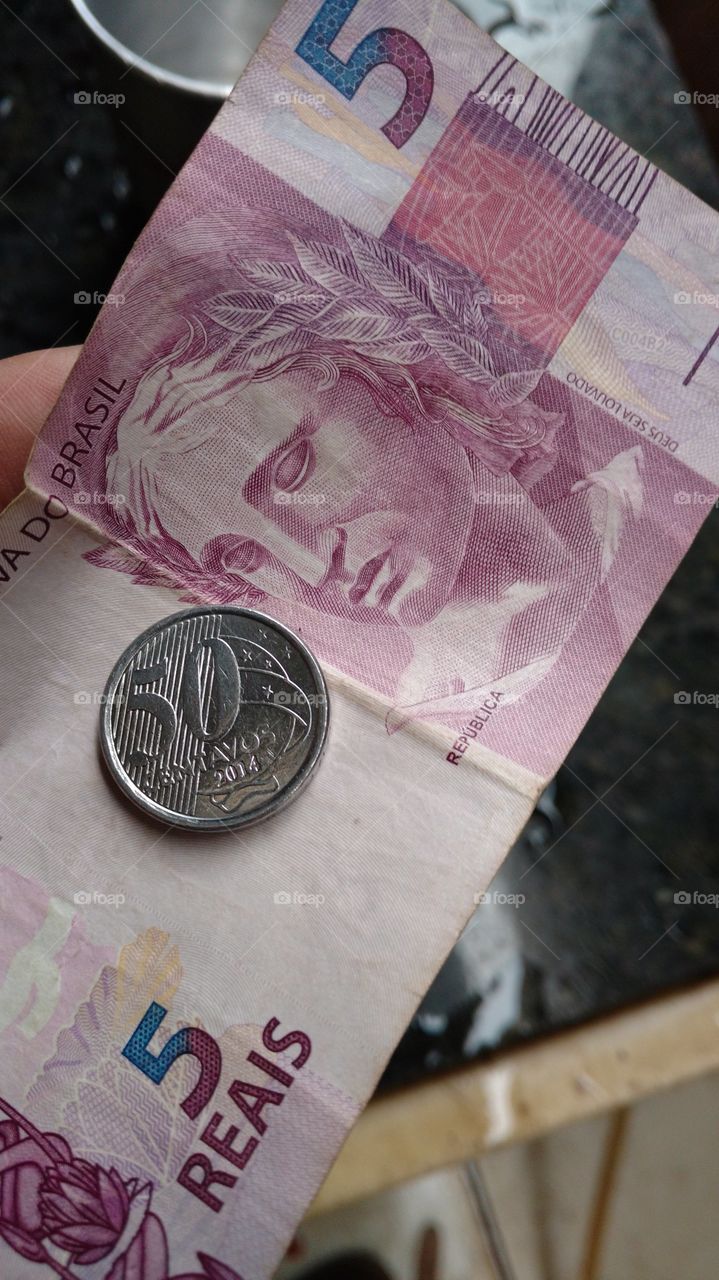 Moeda de 50 centavos e nota de papel de 5 reais.