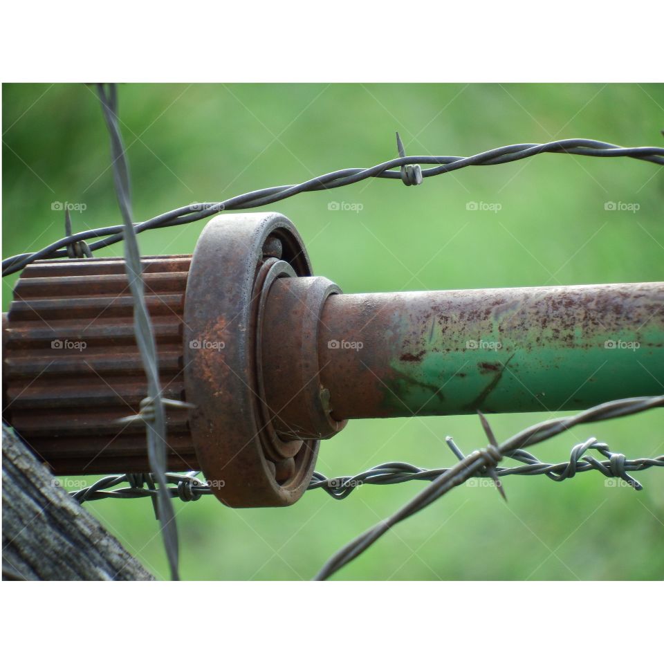 barbed wire fence with metal shaft and green background