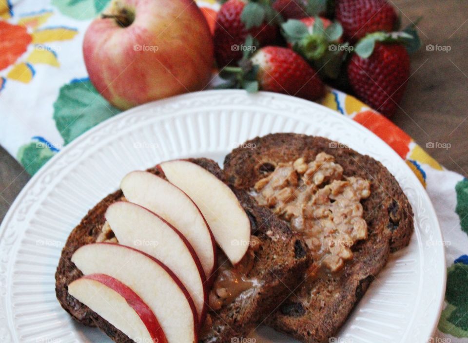 Whole grain raisin toast with crunchy peanut butter and apple slices