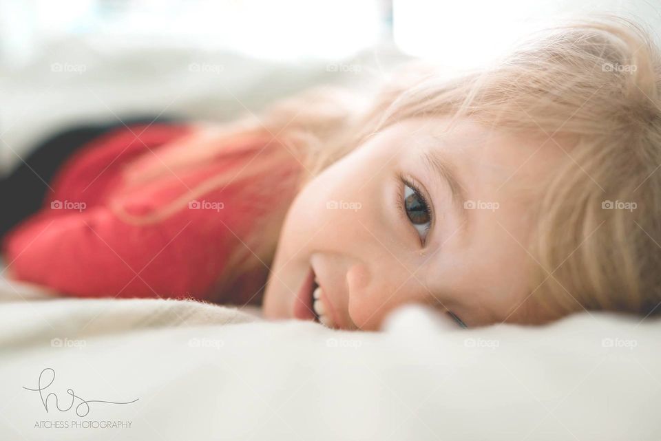 Girl laying on white bed 