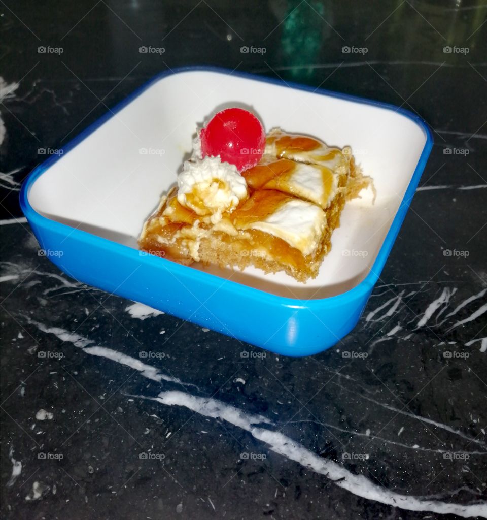 A slice of Egyptian dessert known as kanava, with honey, caramel, cream and cherry added.