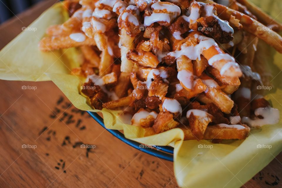 Crisp and tasty buffalo style french fries served up on wooden bar. Spicy and savory game day food.
