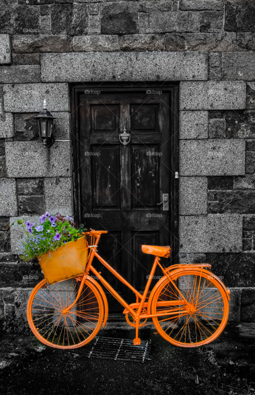 colourful orange bicycle parked in front of a door
