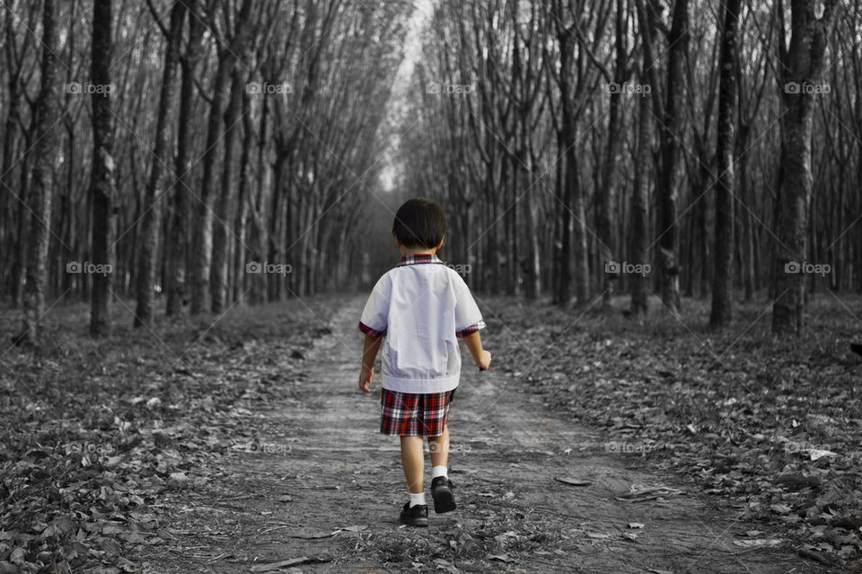 young kid wearing school uniform walking alone in the forest
