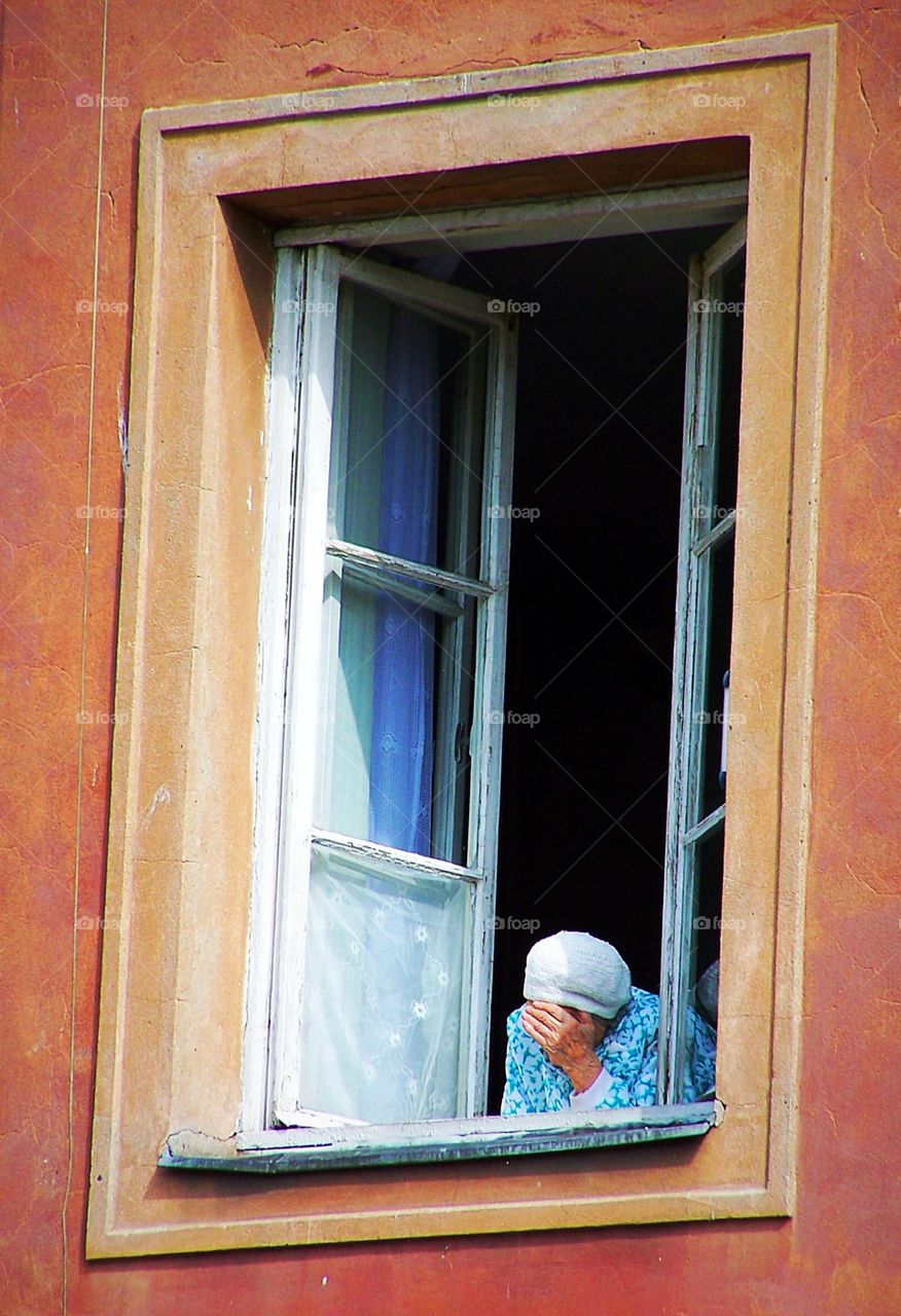 Woman leaning out her window in Warsaw, Poland